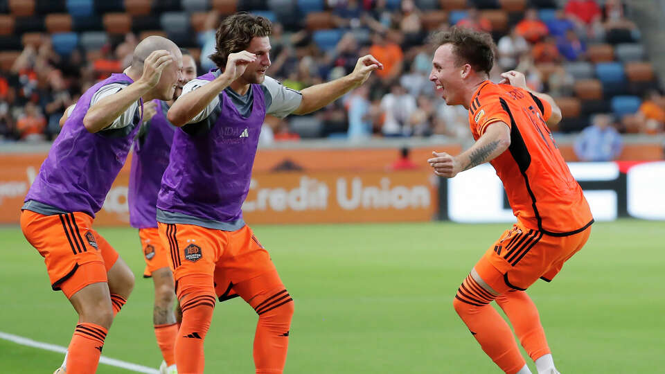 Houston Dynamo's Chase Gasper, left, and Ethan Bartlow, center, dance with forward Corey Baird, right, as they celebrate after a goal by Baird against the Portland Timbers during the first half of an MLS soccer match Sunday, Aug. 20, 2023, in Houston. (AP Photo/Michael Wyke)