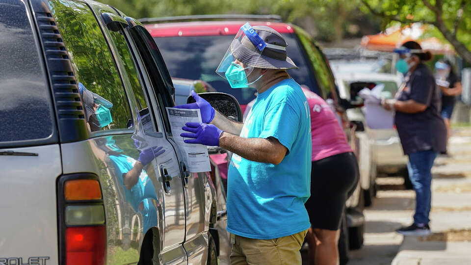 Volunteers with BakerRipley help get paperwork started for folks in line during a drive-through sign-up event for people looking to get utility assistance at BakerRipley on Aberdeen Way on Saturday, July 23, 2022 in Houston.