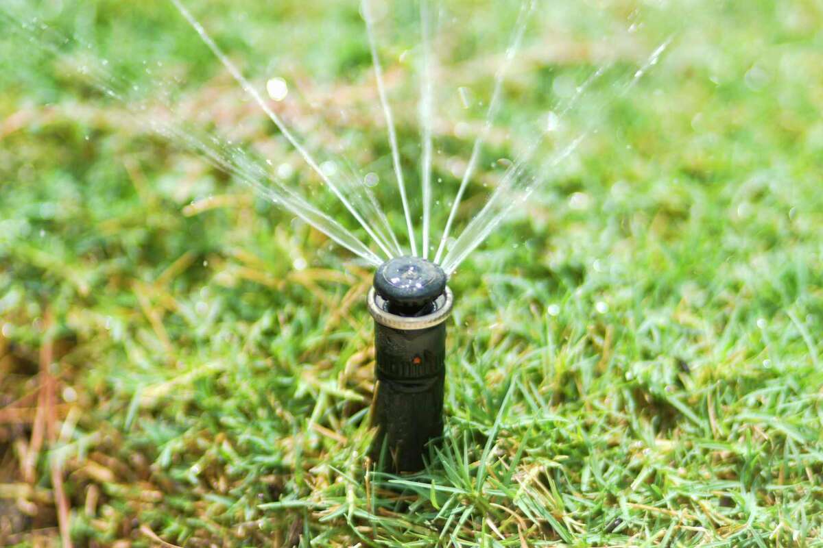 Sprinklers water grass near a home, Tuesday, Aug. 22, 2023, in Conroe.