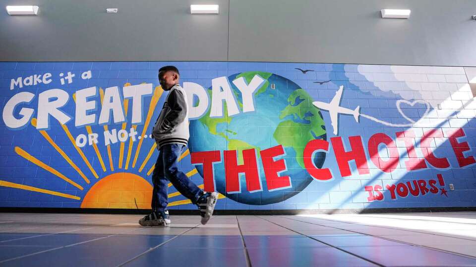 A student walks past an airplane-themed mural at Conroe ISD’s Sam Houston Elementary on Wednesday, Aug. 23, 2023 in Conroe. Principal Chelsea Fuller, the school’s new principal, wanted to create a culture of joy at the school when the students returned. So she got artist Rebecca Steele, to create a 33 by 10 foot mural, featuring the sun, the globe, and an airplane with an inspirational message, on one of the school walls. The school’s mascot is the Jets.