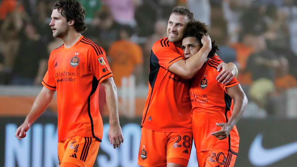 Houston Dynamo's Erik Sviatchenko (28) hugs Adalberto Carrasquilla (20) as they walk off the pitch with Ethan Bartlow (4) after a goal by Carrasquilla against Real Salt Lake during the second half of a U.S. Open Cup soccer semifinal Wednesday, Aug. 23, 2023, in Houston. (AP Photo/Michael Wyke)