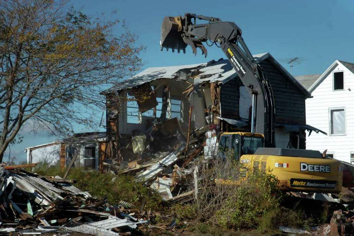 A power excavator digs into one of the cottages on Long Beach West in Stratford, Conn. Friday, Oct. 22nd, 2010. The cottages are being demolished.