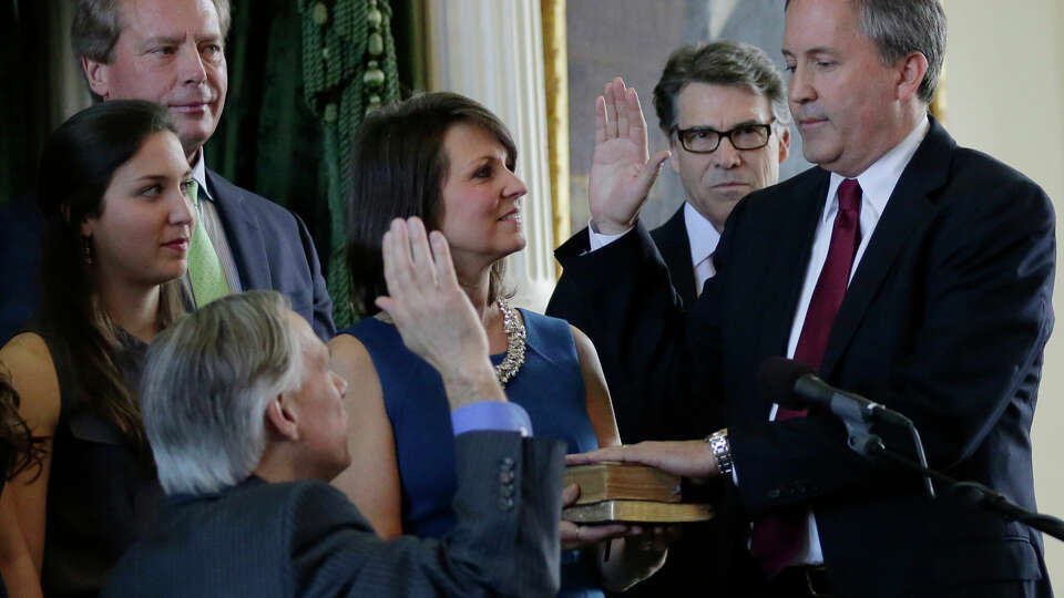 Ken Paxton, right, is sworn in as Texas Attorney General by Gov.-elect Greg Abbott, center, Monday, Jan. 5, 2015, in Austin, Texas. Paxton is joined by his family and Gov. Rick Perry, second from right. (AP Photo/Eric Gay)