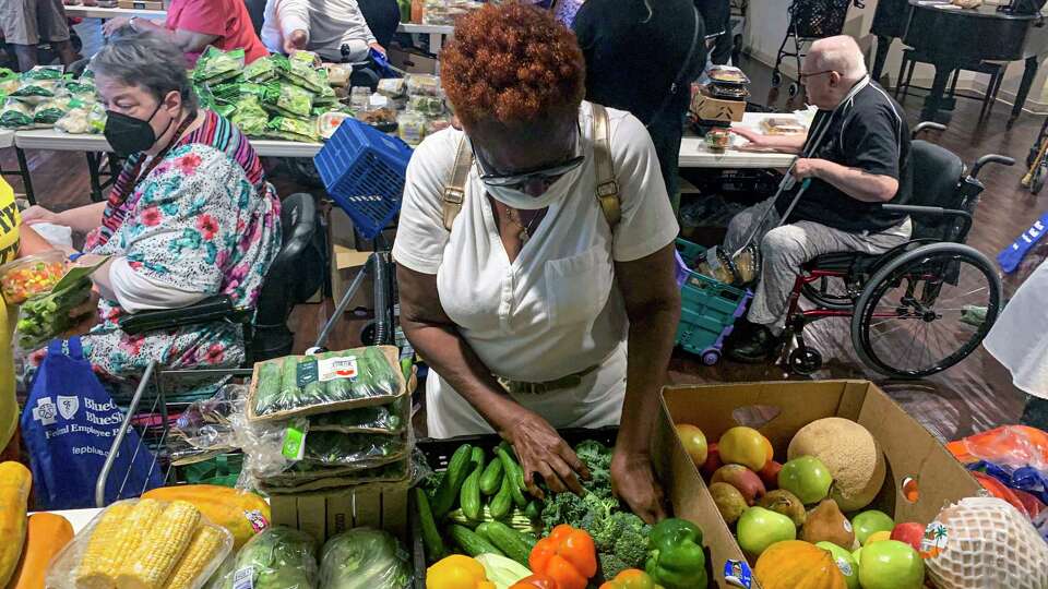 A resident at Houston Heights Tower, a low-income senior highrise, chooses fresh broccoli at Second Servings' monthly PopUp Grocery Store on June 7, 2022.