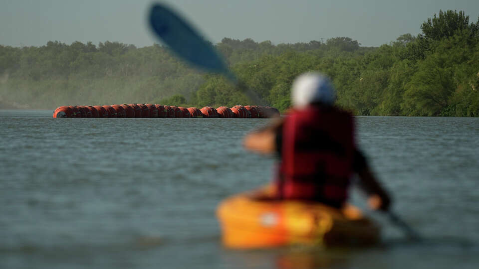 A kayaker approaches large buoys being used as a floating border barrier on the Rio Grande Tuesday, Aug. 1, 2023, in Eagle Pass, Texas. (AP Photo/Eric Gay)