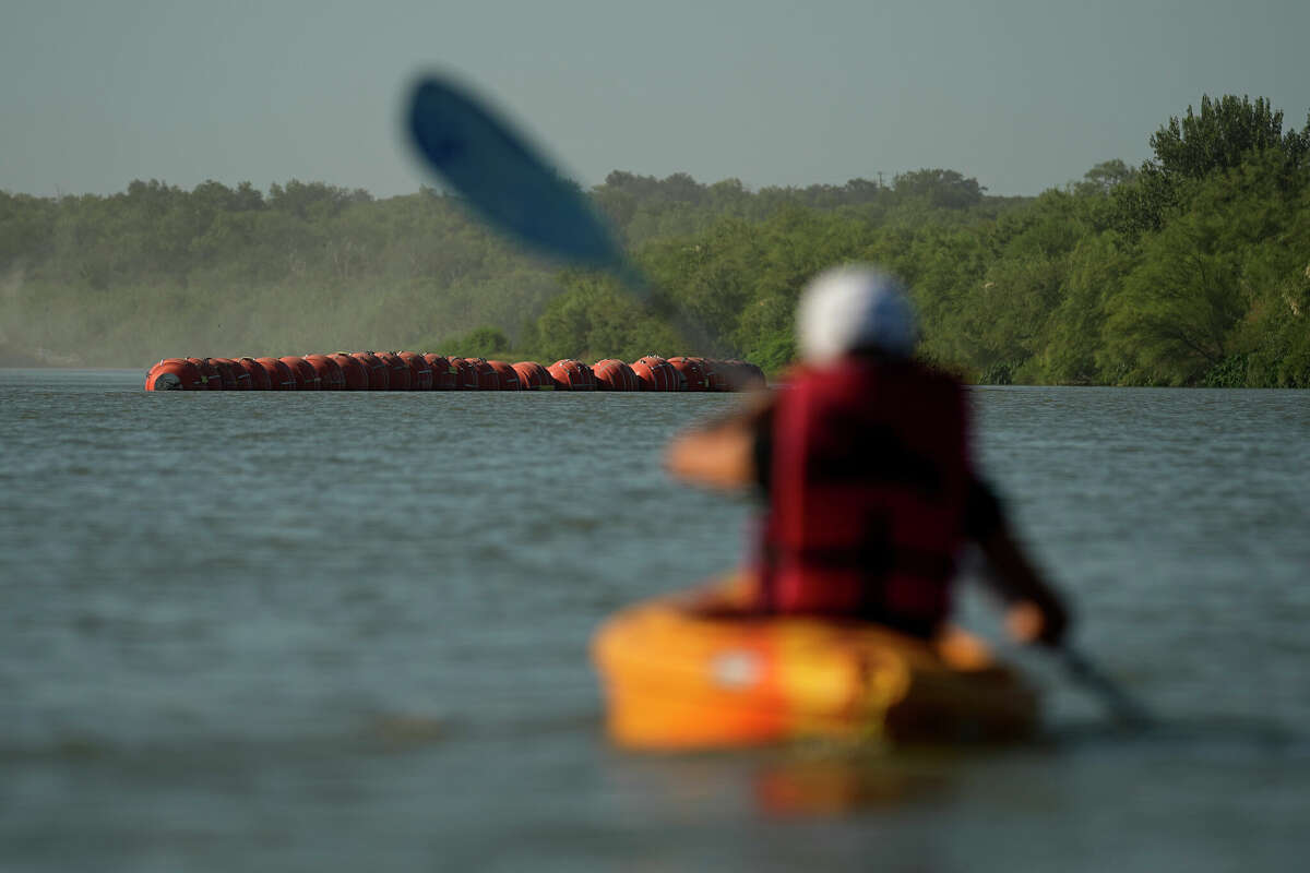 A kayaker approaches large buoys being used as a floating border barrier on the Rio Grande Tuesday, Aug. 1, 2023, in Eagle Pass, Texas. (AP Photo/Eric Gay)