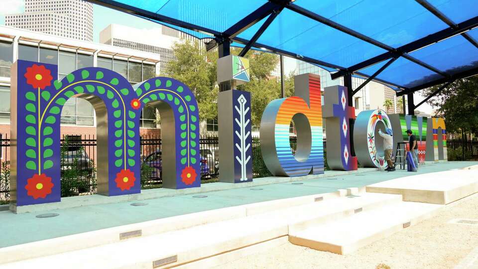 Jacinto Vega and Gustavo Garrison finish a Hispanic Heritage Month-theme mural on the Midtown sign in Bagby Park, Thursday, Sept. 7, 2023, in Houston.