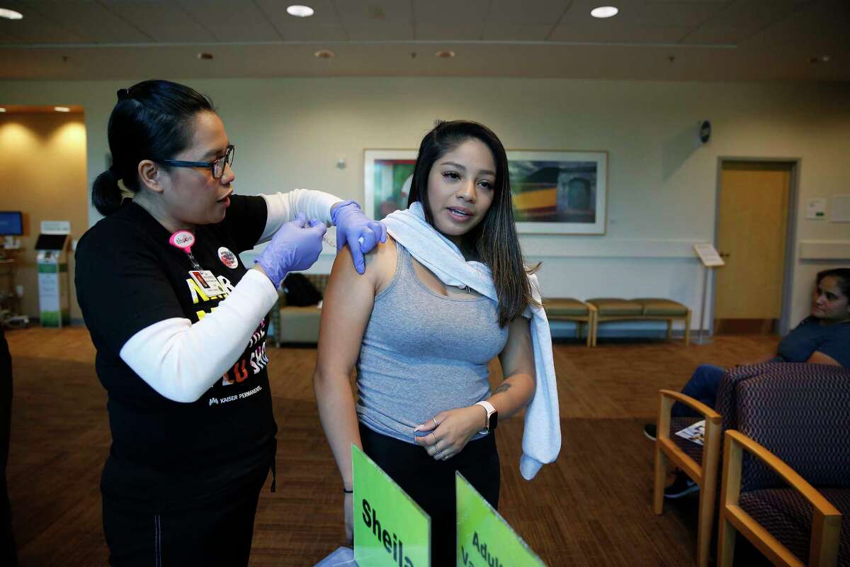 Rubi Hernandez, right, of Sunnyvale, gets a flu shot at the Kaiser Permanente Santa Clara flu clinic from Sheila Aldana in October 2019. Late October is the ideal time for flu vaccination in California.