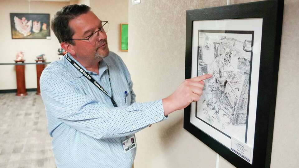 Conroe ISD Director of Fine Arts Robert Horton points out words embedded in The Woodlands High School senior Paul Zeyer's piece entitled 