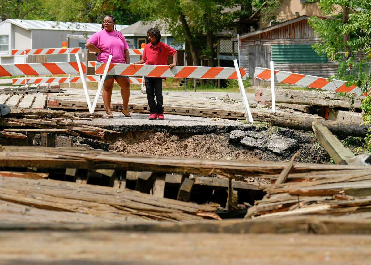 Sa'ke Early and her son, Za’Vion Crawford, look at the remains of a wooden bridge in the Walnut Cove neighborhood of Willis after it collapsed when a 30-ton concrete truck smashed through the beams Thursday morning while crossing, Friday, Sept. 15, 2023. The driver of the truck was not injured in the accident. The wooden bridge, near the intersection of Maywood and Sassafras streets, was constructed in 1987, and has a 4-ton weight limit, according to signs posted near the bridge.