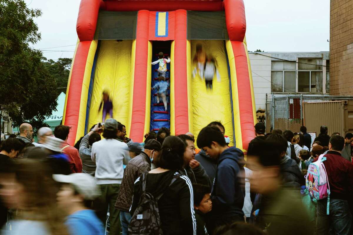 Kids slide down the bounce house slide at the Night Market in the Sunset District on Friday. San Francisco Supervisor Joel Engardio said three blocks wasn’t enough for the inaugural night market.
