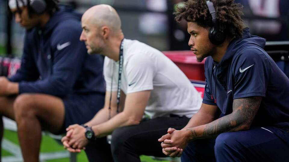 Houston Texans safety Jalen Pitre, right, sits on the bench watching his teammates warm up before an NFL football game against the Indianapolis Colts Sunday, Sept. 17, 2023, in Houston.