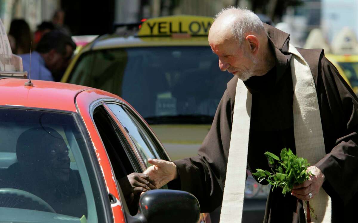 Father Louie Vitale greets a cab driver after sprinkling a taxi with holy water at the annual Blessing of the Taxicabs outside St. Boniface Church on Golden Gate Avenue in San Francisco in August 2005.