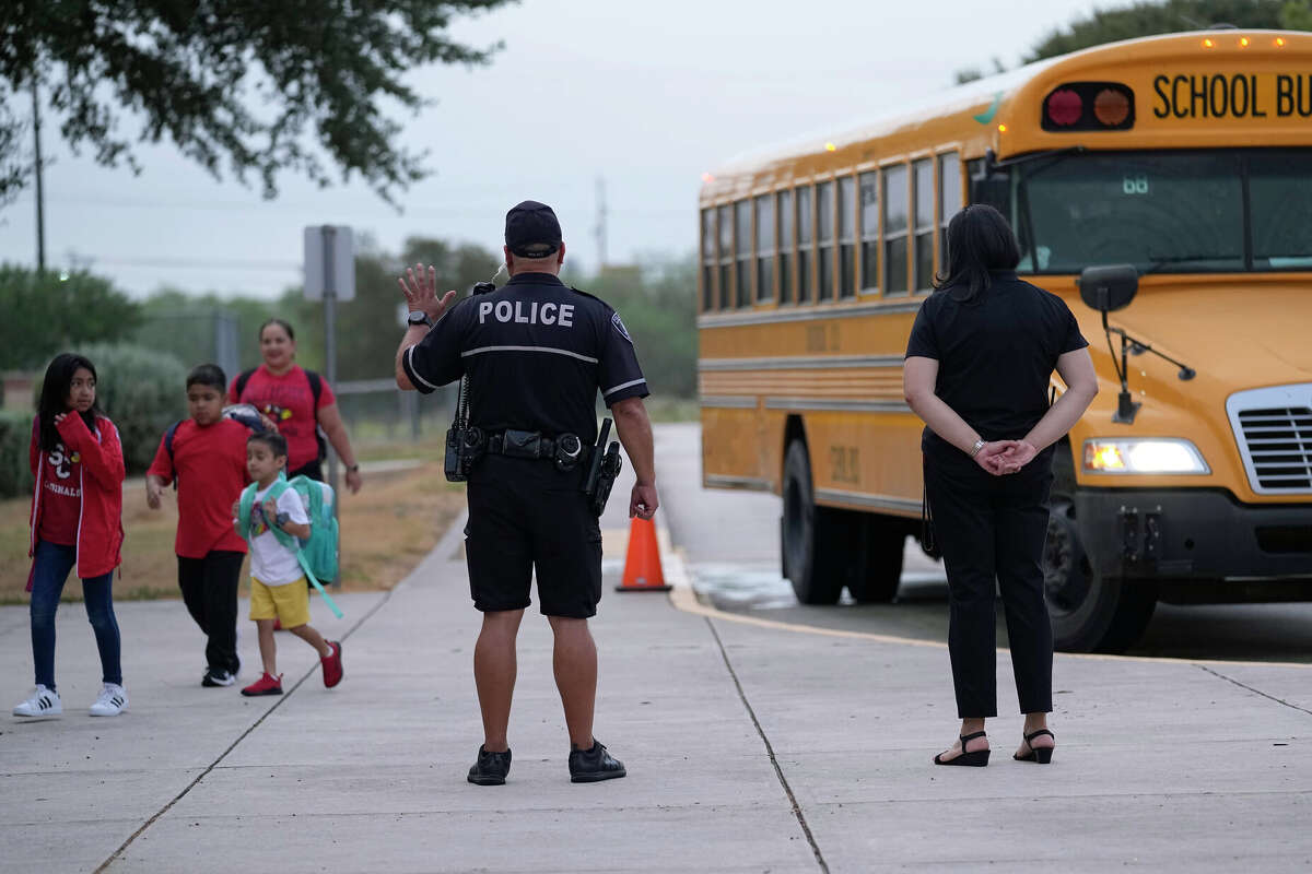 Southside Independent School District police officer Ruben Cardenas, center, keeps watch as students arrive at Freedom Elementary School, Wednesday, Aug. 23, 2023, in San Antonio. Most Texas school districts say they are unable to comply with a new law requiring armed officers on every campus. The mandate was one of Republican lawmakers' biggest acts following the Uvalde school shooting in 2022 that killed 19 children and two teachers. (AP Photo/Eric Gay)