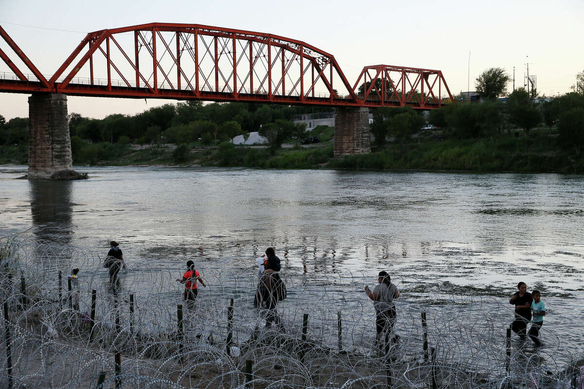 Los inmigrantes buscan una salida a través de alambres de púas en las orillas estadounidenses del Río Grande, cerca de Eagle Pass.