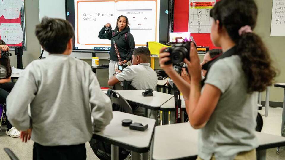 Photographer Theresa Thomas teaches kids how to use their cameras during a photography DYAD class at Lawson Middle School on Thursday, Sept. 21, 2023 in Houston. Houston ISD state-appointed superintendent Mike Miles introduced the DYAD program at the district's schools this year, where contractors come to the school to teach programs like photography, gardening, boxing, golf, yoga, spin, videography, piano, guitar.