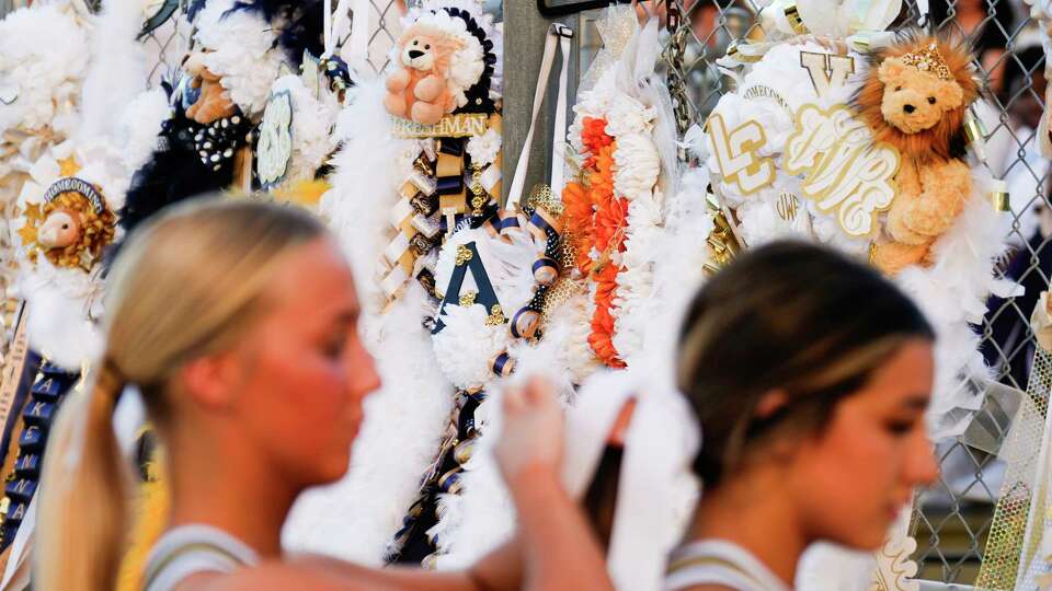 Lake Creek cheerleaders get ready as homecoming mums hang from the stands before a District 10-5A Division II high school football game at Montgomery ISD Stadium, Friday, Sept. 22, 2023, in Montgomery.