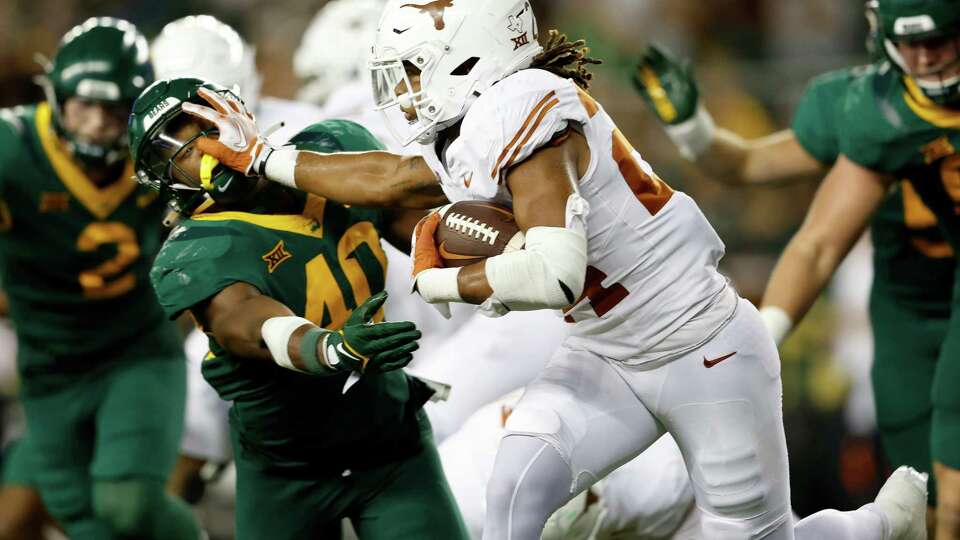 WACO, TEXAS - SEPTEMBER 23: Jonathon Brooks #24 of the Texas Longhorns give a stiff arm to Mike Smith Jr. #40 of the Baylor Bears in the third quarter at McLane Stadium on September 23, 2023 in Waco, Texas.