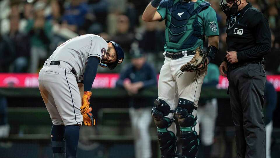 Houston Astros' Jose Altuve, left, reacts after getting hit by a pitch during the ninth inning of a baseball game against the Seattle Mariners, Monday, Sept. 25, 2023, in Seattle. Mariners catcher Cal Raleigh, second from right, looks on. (AP Photo/Stephen Brashear)