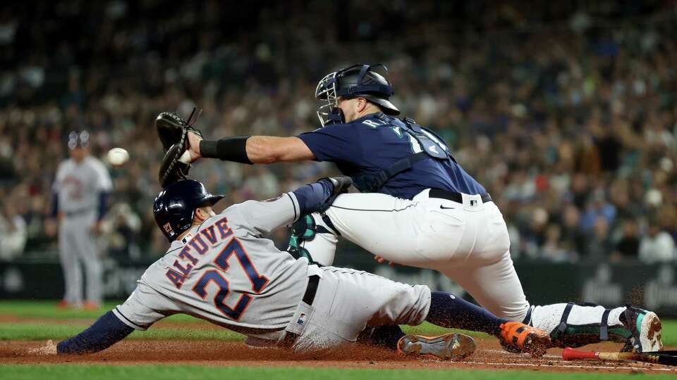 SEATTLE, WASHINGTON - SEPTEMBER 26: Jose Altuve #27 of the Houston Astros is tagged out at home plate by Cal Raleigh #29 of the Seattle Mariners during the first inning at T-Mobile Park on September 26, 2023 in Seattle, Washington.