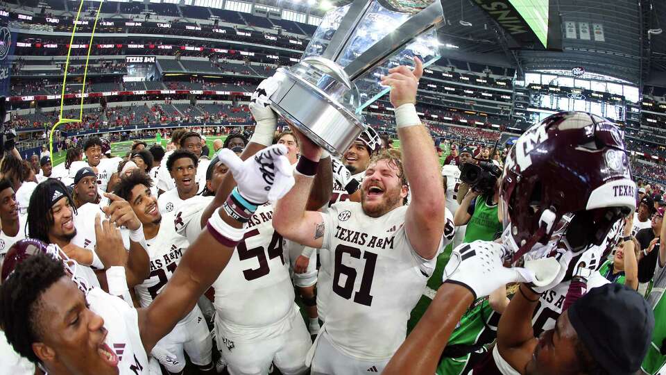 ARLINGTON, TEXAS - SEPTEMBER 30: The Texas A&M Aggies celebrate with the trophy after the win over the Arkansas Razorbacks during the Southwest Classic at AT&T Stadium on September 30, 2023 in Arlington, Texas.