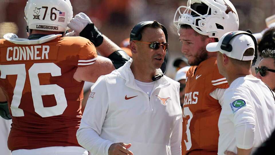 Texas head coach Steve Sarkisian, center, talks with quarterback Quinn Ewers (3) during the first half of an NCAA college football game in Austin, Texas, Saturday, Sept. 30, 2023. (AP Photo/Eric Gay)