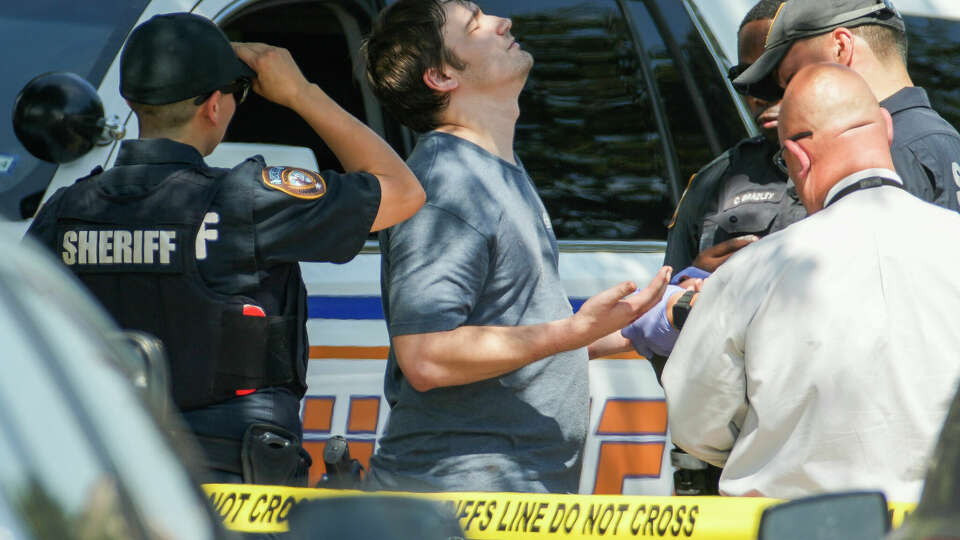 A man reacts as crime scene investigators with the Harris County Sheriff's Office gather evidence at the scene of a shooting where four people were shot and two females were killed, Sunday, Oct. 1, 2023, in Houston. The two other people shot were transferred to a hospital.