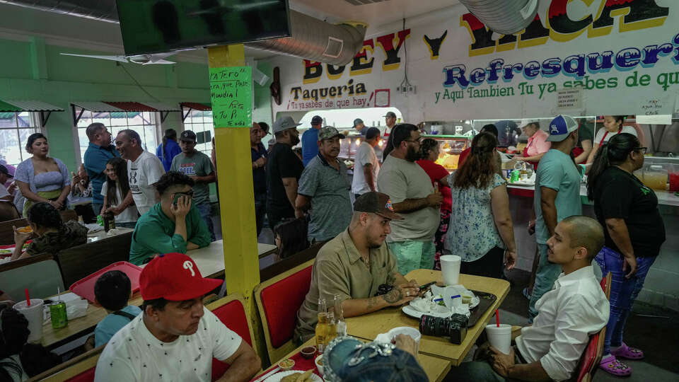 Max Hummels and Dario de Leon sit down to eat during a busy day at the markets original food stop, Vaca Y Buey Tacos, on Sunday, July 9, 2023 in Houston.