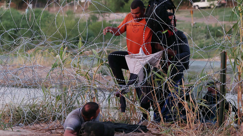 Migrants get through concertina wire after crossing the Rio Grande into Eagle Pass, Texas, Thursday, Sept. 21, 2023. A surge of migrants crossing the Rio Grande into the U.S. continued Thursday.