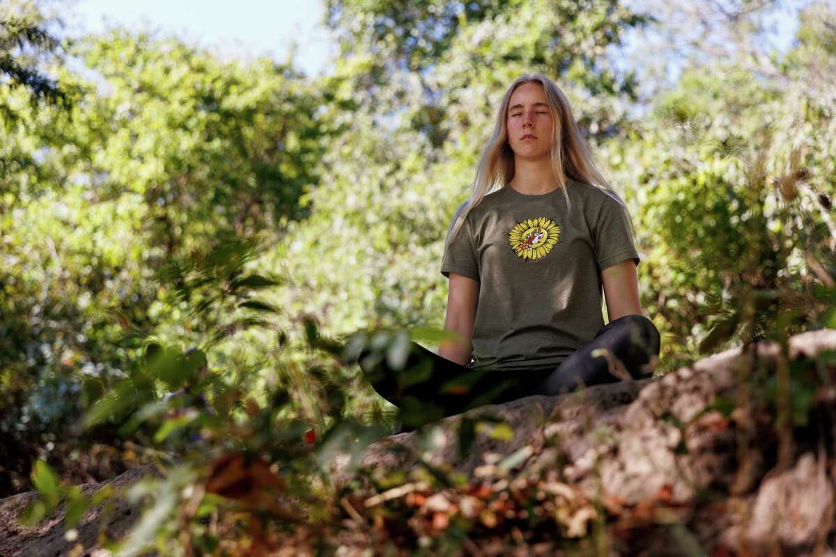 Paige Bensing meditates as Trinity University professor Laura Allen, not pictured, asks her students to quietly listen to the sounds around them during a recent field trip to the Guadalupe River State Park.