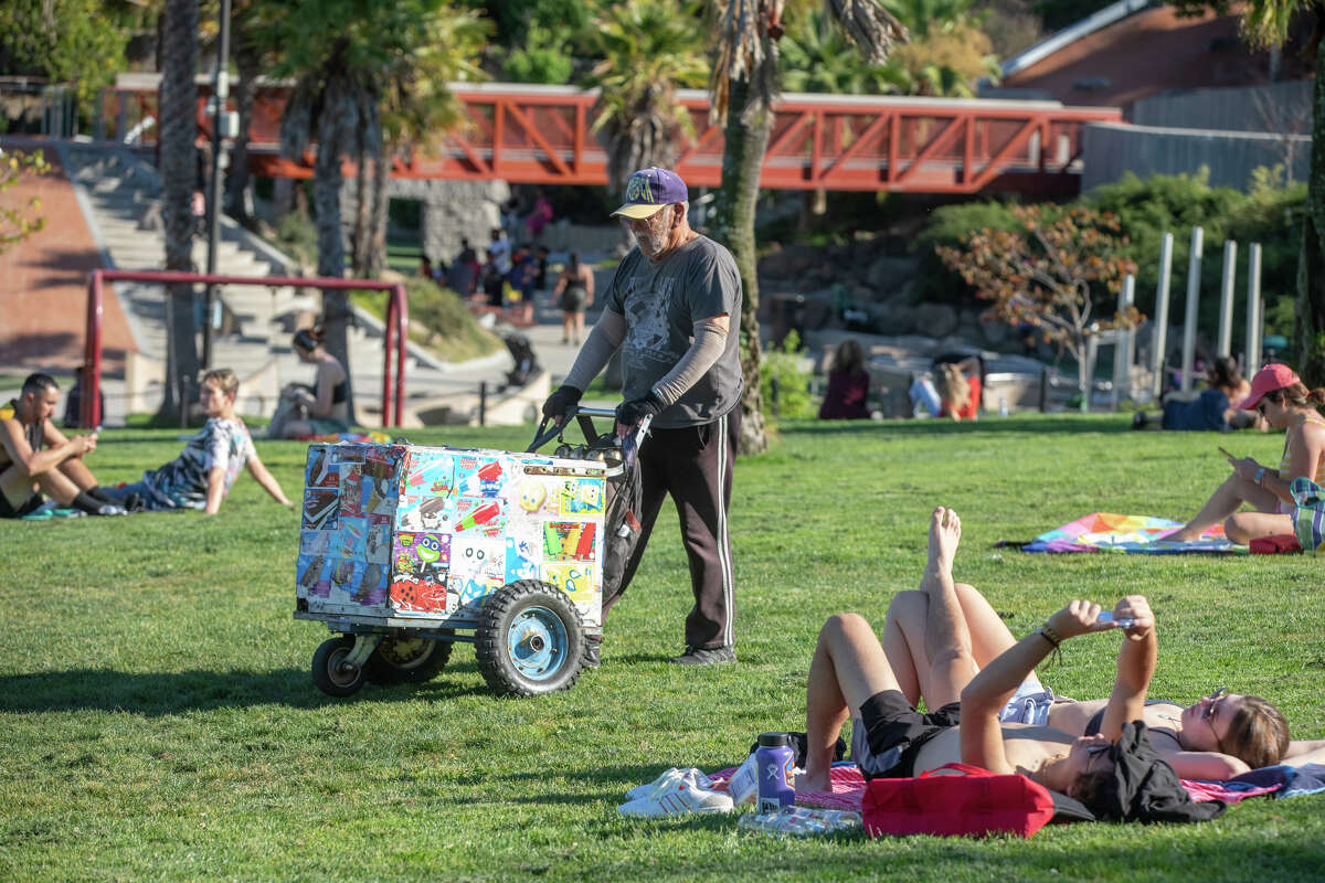 An ice cream vendor walks through people hanging out in Dolores Park in San Francisco, Calif. during a warm weather day on October 4, 2023.