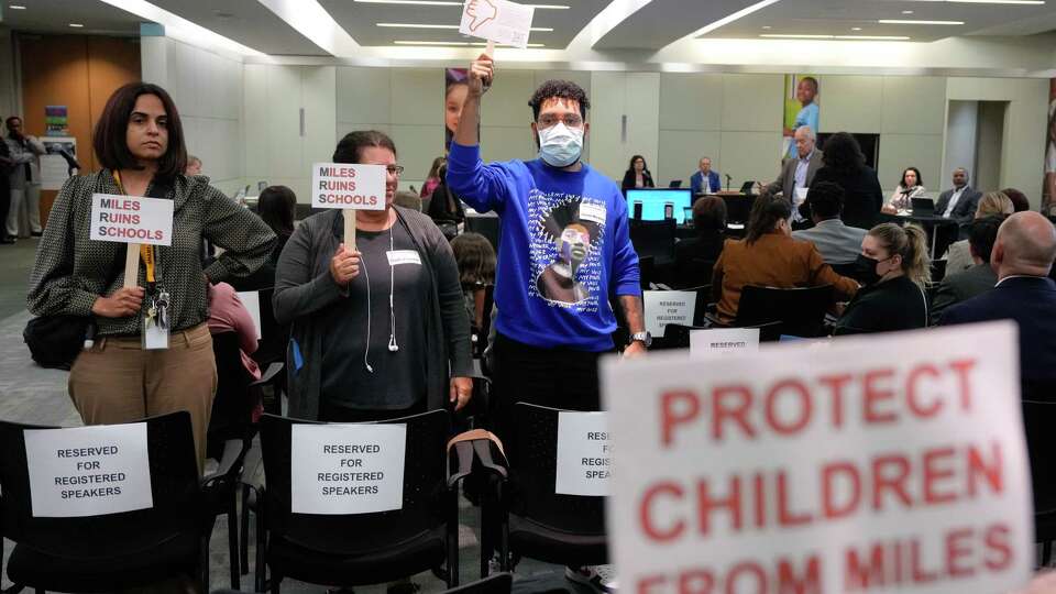 The Houston ISD Board of Trustees monthly agenda review meeting attendees Anita Wadhwa, from left, Ruth Hoffman Lach and Xavier Mickens turn their back and raises signs to show disapproval as superintendent Mike Miles begins his presentation during the meeting on Thursday, Oct. 5, 2023 at in Houston.