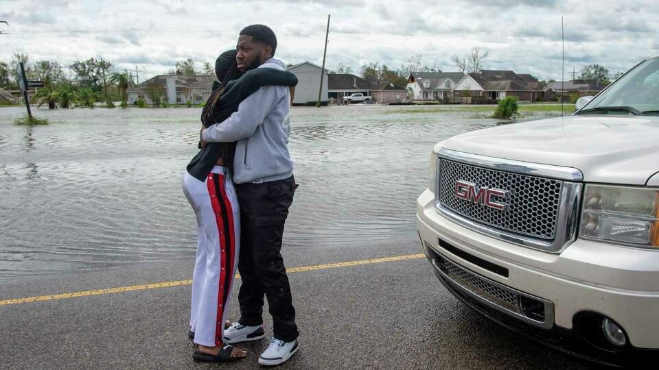 Family members reunite on a flooded roadway in Louisiana's St. John the Baptist Parish during an evacuation on the morning after Hurricane Ida, Monday, Aug. 30, 2021. (Chris Granger/The Times-Picayune/The New Orleans Advocate via AP)