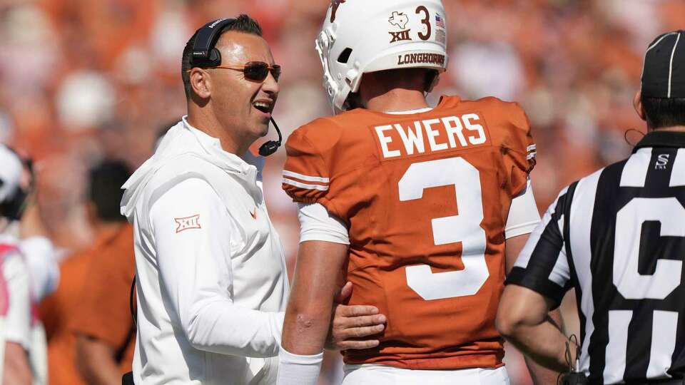 Texas head coach Steve Sarkisian, left, confers with quarterback Quinn Ewers (3) during the first half of an NCAA college football game against Oklahoma at the Cotton Bowl in Dallas, Saturday, Oct. 7, 2023. (AP Photo/LM Otero)