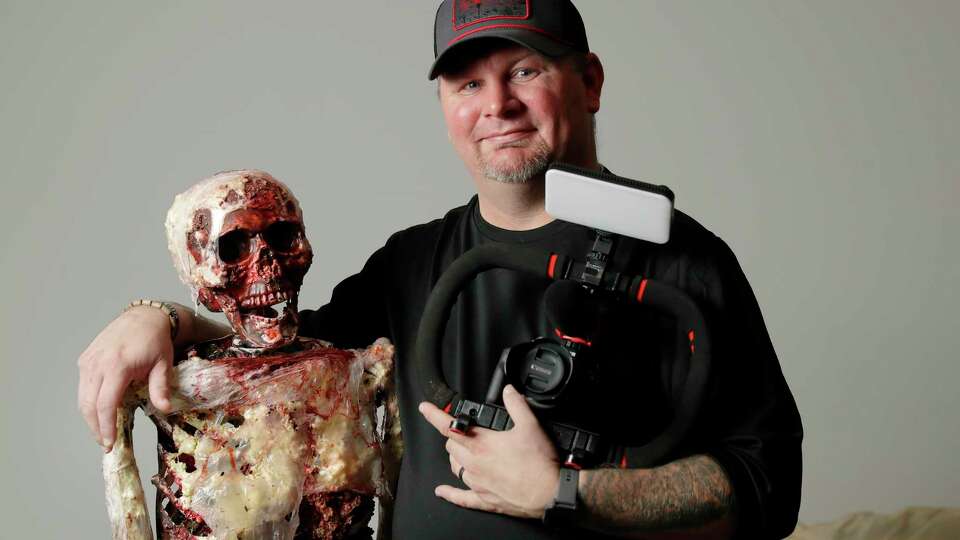 Dustin Tamplin, a horror movie enthusiast, podcaster and film maker with ÒDarrylÓ, one of his movie props, and the main camera he used to film at his home Thursday, Oct. 12, 2023 in Magnolia, TX.