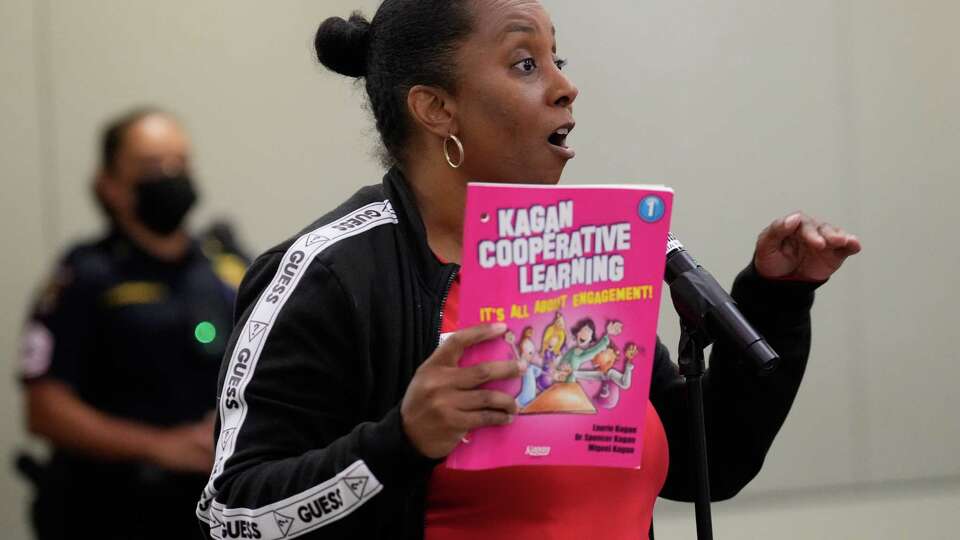 Michelle Williams, president of the Houston Education Association, using a Kagan Cooperative Learning book to speak against the approval of new evaluation system for principals during the public comment session of the Houston ISD Board of Trustees meeting on Thursday, Oct. 12, 2023 at Hattie Mae White Educational Support Center in Houston.