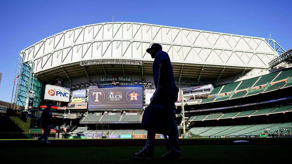 A Texas Rangers coach walks on the field during workouts ahead of Game 1 of the ALCS at Minute Maid Park on Saturday, Oct. 14, 2023, in Houston.