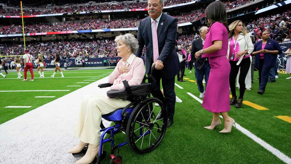 Houston Texans co-owner Janice McNair, left, is seen in a wheelchair pushed by her son and CEO Cal McNair before an NFL football game Sunday, Oct. 15, 2023, in Houston.