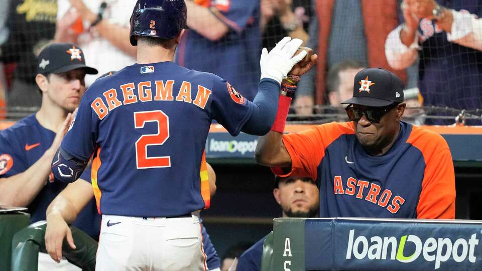 Houston Astros Alex Bregman, center, gets a high-five from manager Dusty Baker, right, after hitting a solo home run off Texas Rangers pitcher Nathan Eovaldi in the fourth inning during Game 2 of the American League Championship Series at Minute Maid Park on Monday, Oct. 16, 2023, in Houston.