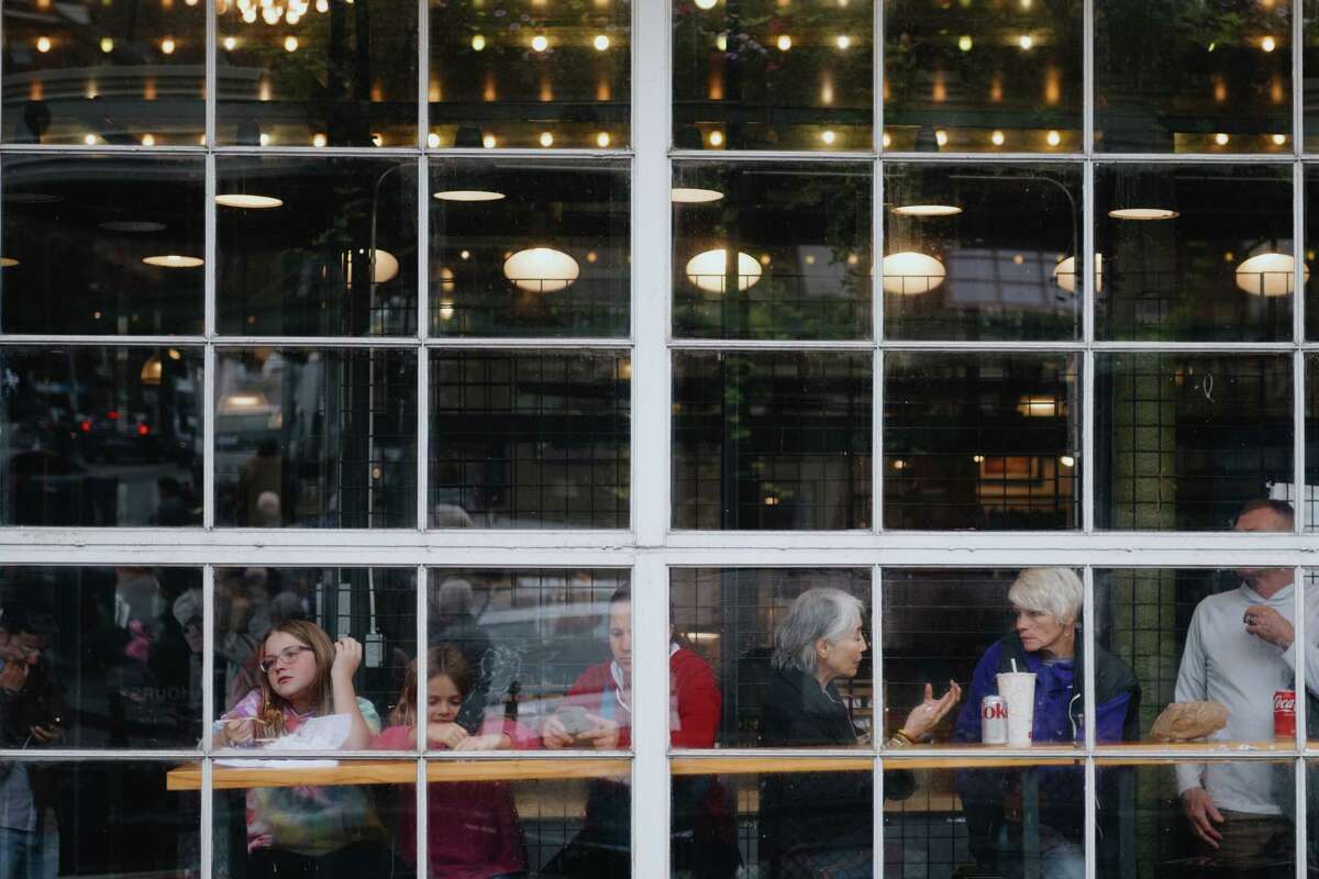 Visitors take a break from the shops at Pike Place Market on Monday Oct. 9, 2023.