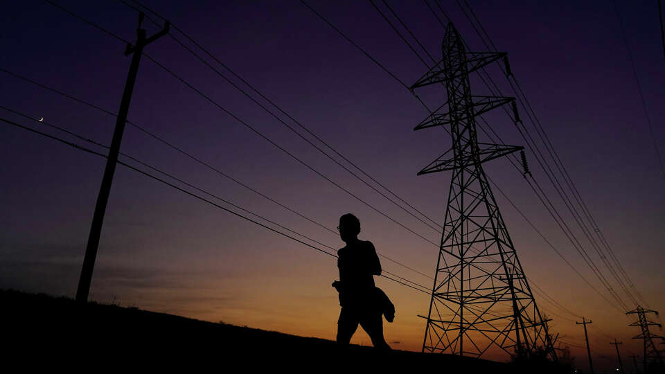 A jogger passes power lines in San Antonio in August, when record-high temperatures were a daily test for the state power grid.