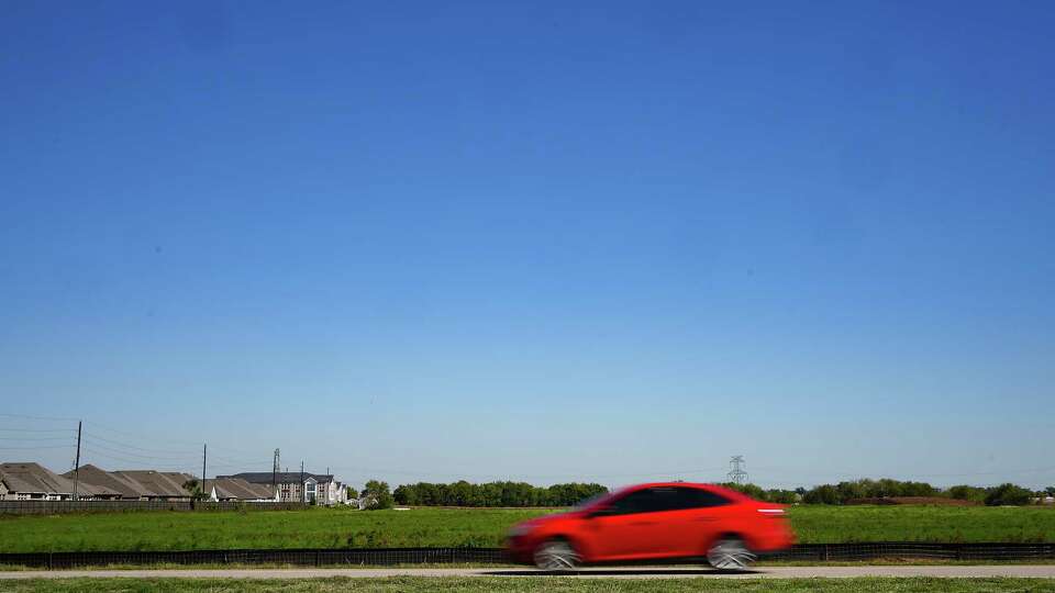 A car drives past a proposed location of a new elementary school as part of Fort Bend ISD Construction off of Harlem Road near Harvest Garden Boulevard on Tuesday, Oct. 17, 2023 in Richmond. Fort Bend ISD has planned a new school on the site of the former Harlem Prison Farm, activists are worried there is a cemetery on the property.