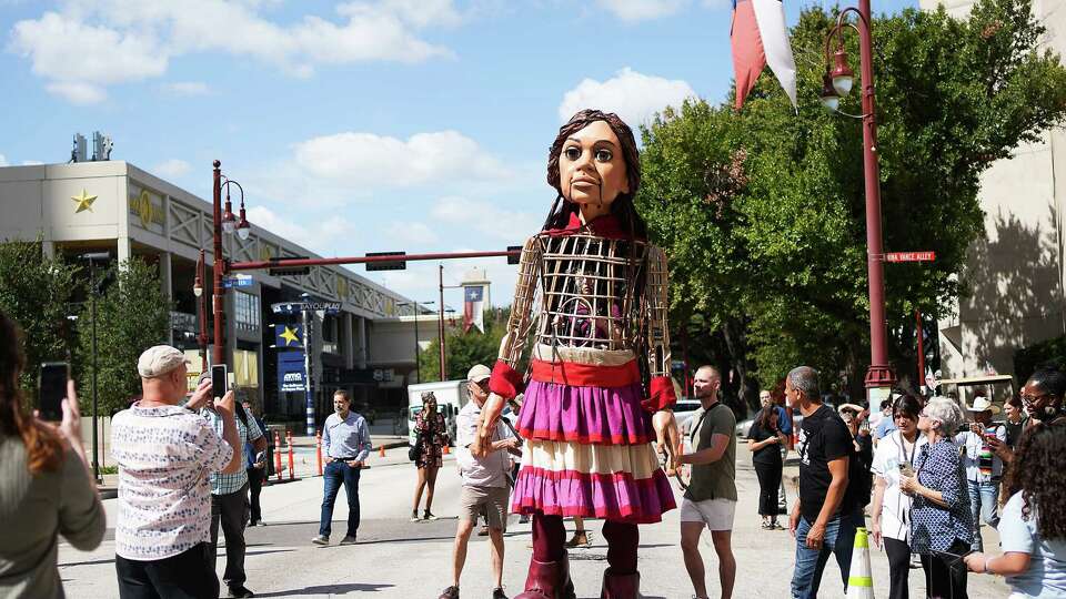 Little Amal, a 12-foot puppet of a 10-year-old Syrian refugee girl, make its way in downtown Houston's Theater District on Thursday, Oct. 19, 2023.