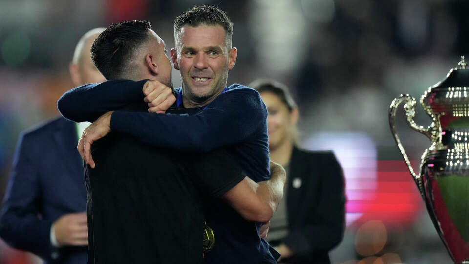 Houston Dynamo coach Ben Olsen hugs team captain Hector Herrera as Herrera takes the stage to collect the trophy, after the team defeated Inter Miami 2-1 in the U.S. Open Cup final soccer match Wednesday, Sept. 27, 2023, in Fort Lauderdale, Fla. (AP Photo/Rebecca Blackwell)