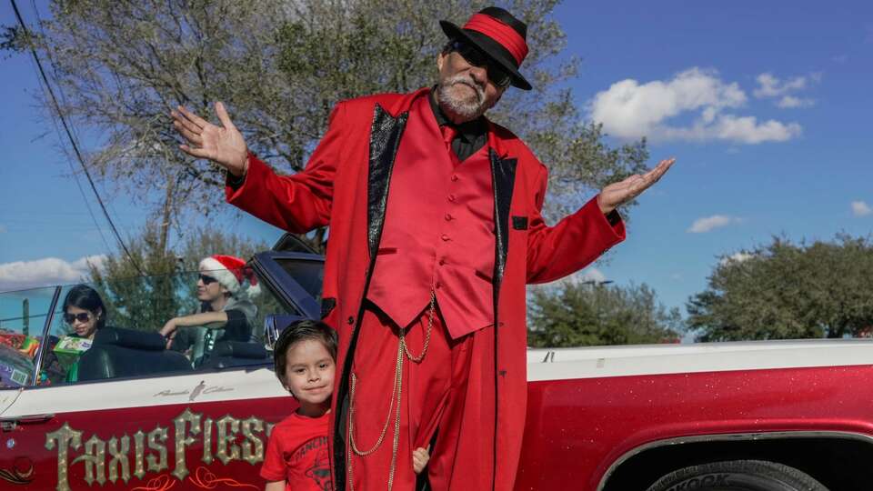 Rene Hernandez, 3, stands with his grandfather, Pancho Claus, Richard Reyes, as he hands out toys to children in the neighborhood of Second Ward for Dia De Los Reyes / Three Kings Day on Friday, Jan. 6, 2023 in Houston.