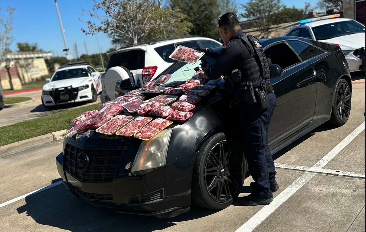 A Precinct 4 deputy constable piles meat on the hood of a car during a traffic stop on Wednesday, Nov. 1, 2023.