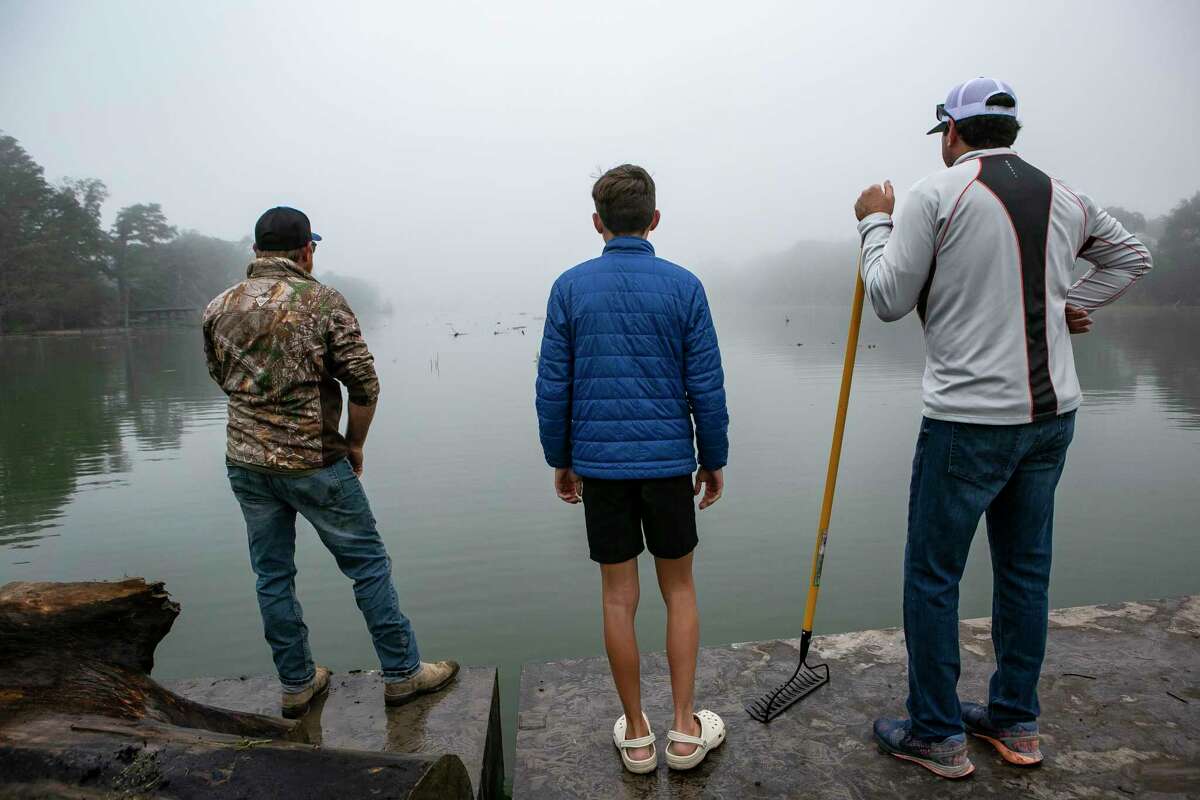 From left, Chris Cambron, Luke Bryant and Hagan Cohle keep an eye out for logs and debris in Lake Dunlap on Nov. 4.