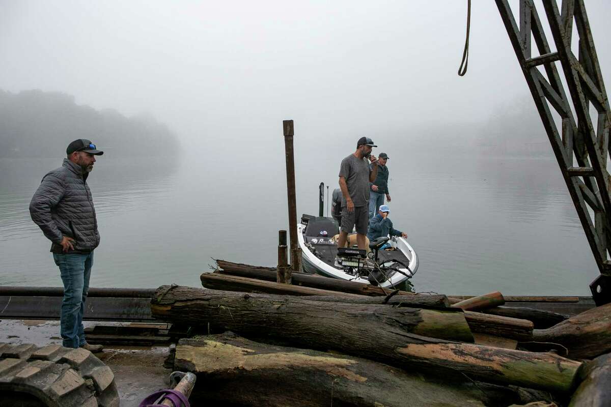 From left, NB Boathouse owner Chip Bryant and volunteers Philip Thompson, Ted Jackson and Thomas Howe help clean up logs and vegetation that accumulated in Lake Dunlap while it was empty over the past four years.