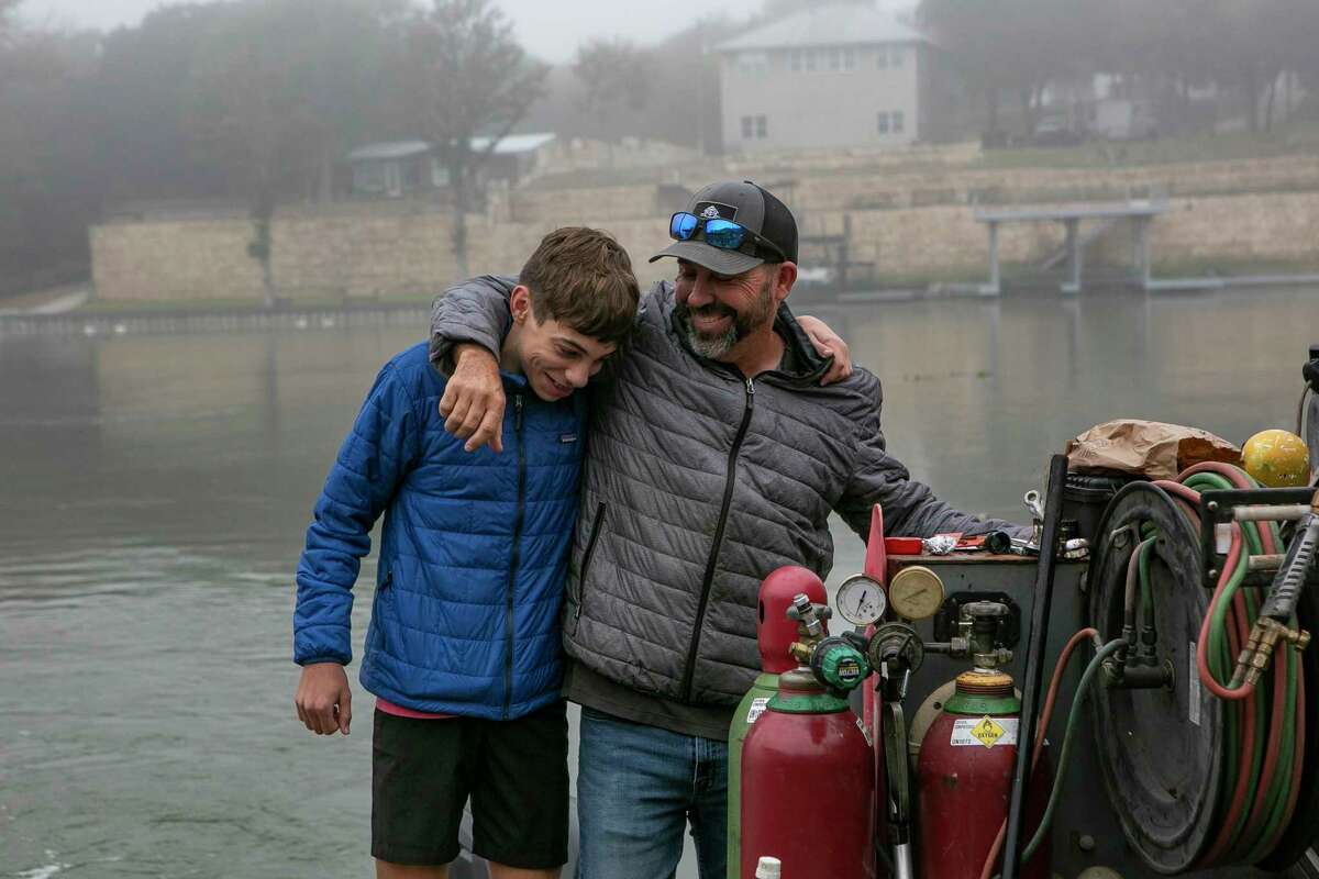 Chip Byrant, right, hugs his son Luke Bryant during a lake cleanup day on Lake Dunlap on Nov. 4. The lake has recently been refilled after a dam failure in 2019 caused it to drain. 