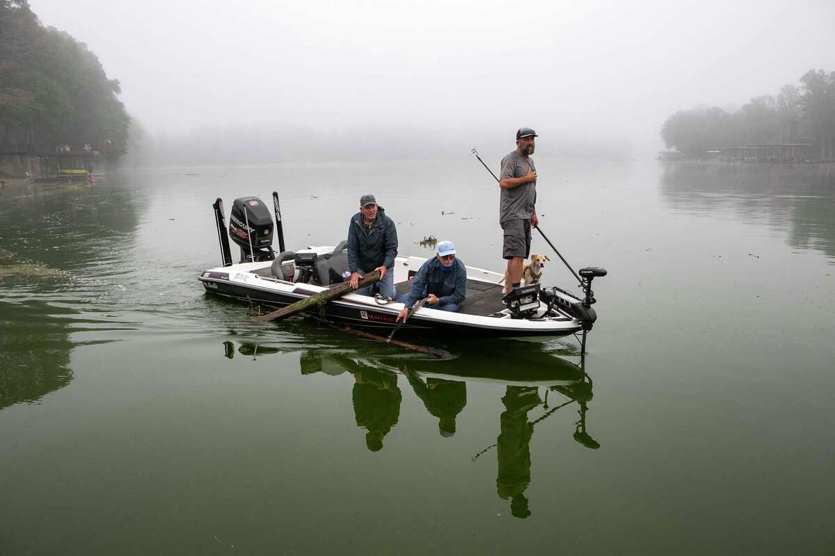 Volunteers Thomas Howe, Ted Jackson and Philip Thompson help clean up logs and vegetation that accumulated in Lake Dunlap while it was empty over the past four years.